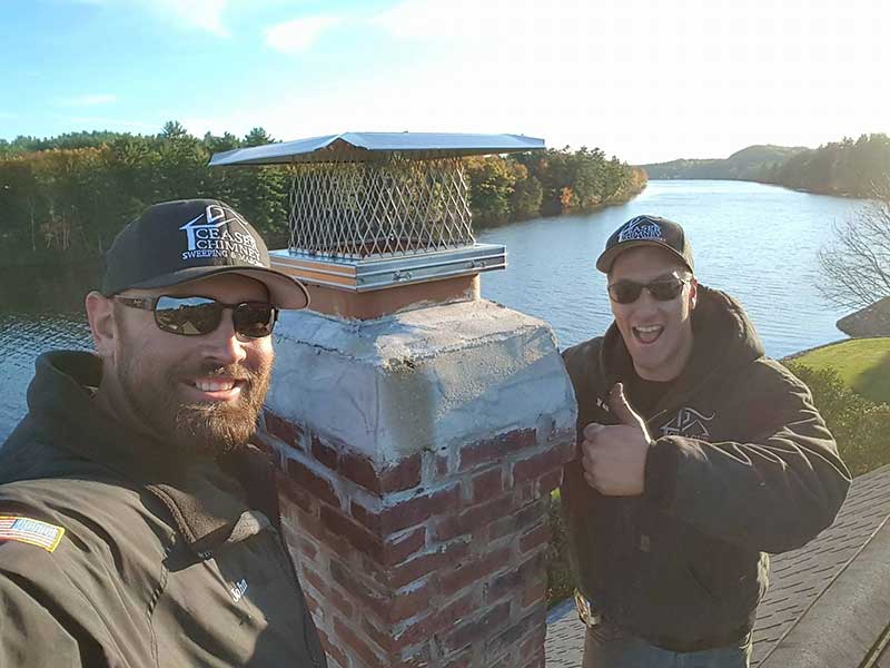 two men smiling next to a chimney