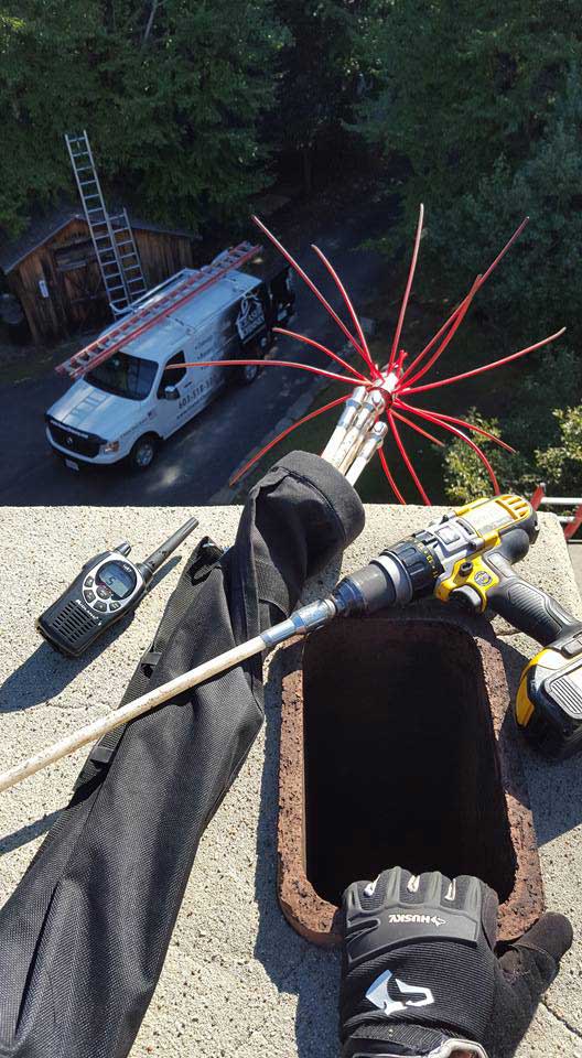 Ceaser's Chimney original photo of tech inspecting and cleaning flue with truck in background