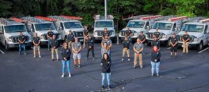 Team Photo 21 team members standing in front of 7 work vans