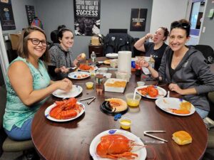 Team Photo 4 ladies in the office eating lobster and shrimp in conference room