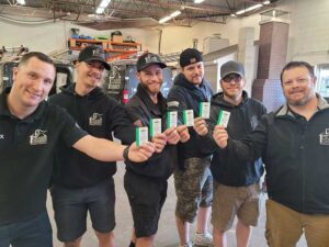 Team Photo of six guys in warehouse wearing logo shirts holding cards in front of them