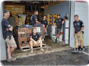 Team Photo - 6 guys with logo shirts standing in warehouse